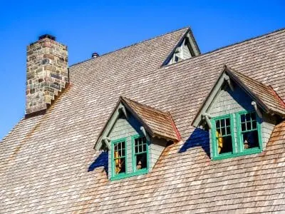 Cedar shake roof with twin dormers and a stone chimney