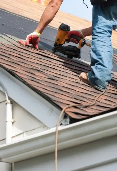 Roofer installing architectural shingles along a roof edge