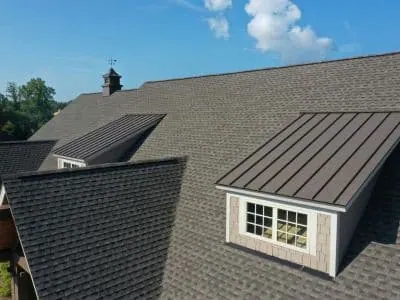 Dark architectural shingle roof with a standing-seam metal dormer accent