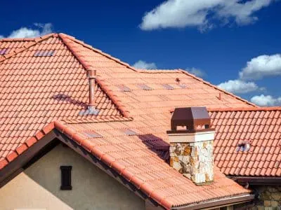 Terracotta Spanish tile roof with a stone chimney